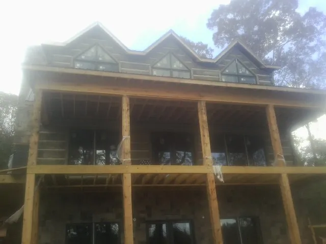 Dormers and porch framing on a large log home under construction — Roof Coating work by our crew in Roulette