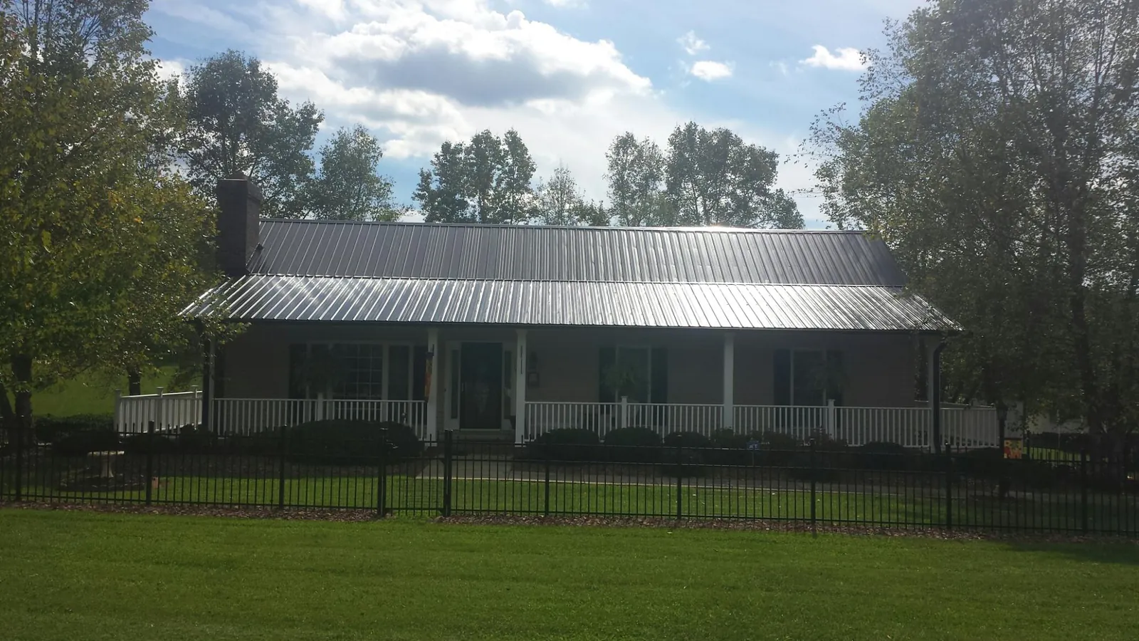 Gray metal roof on a brick ranch with a full width front porch — Gutter Guard Installation work by our crew in Roulette