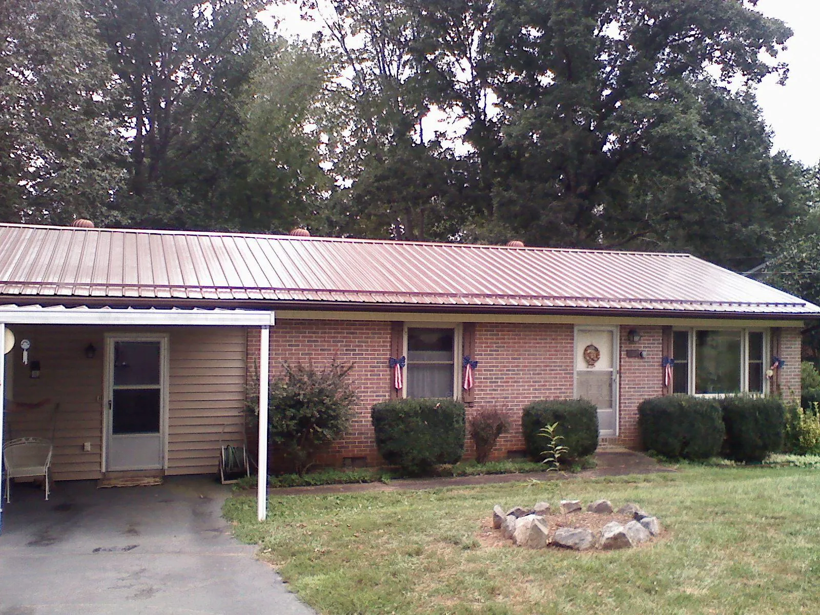 Bronze metal roof and carport on a brick ranch home — Roof Repair work by our crew in Roulette