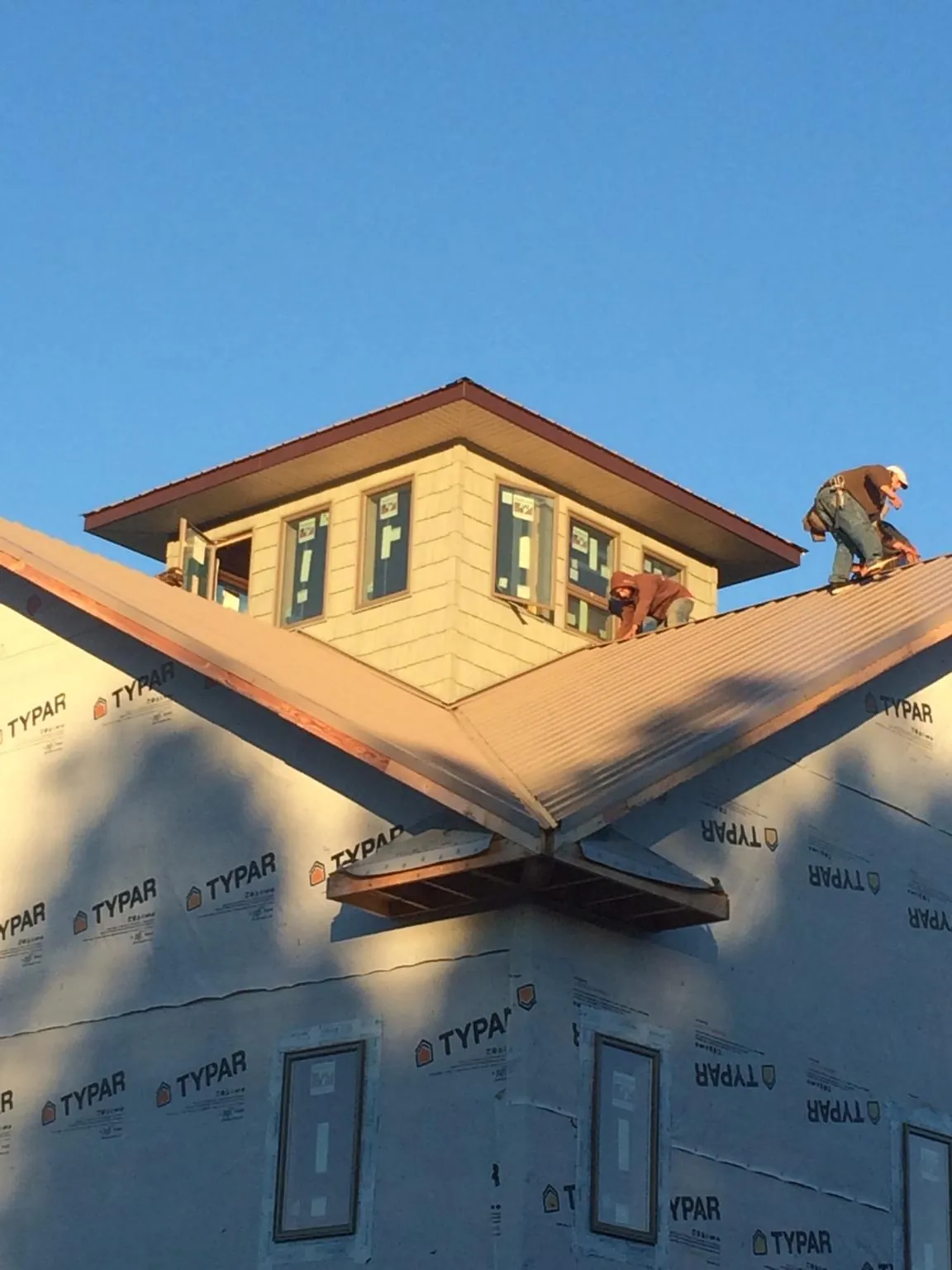 Roofers working around a rooftop cupola on a new metal roof at sunset — Roof Waterproofing in Roulette by Roofing Brothers